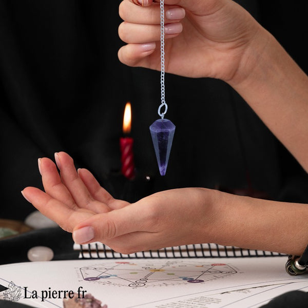 Pendule en pierre d'améthyste facetté, 100 % naturel, avec chaînette argentée de 17 cm, posé sur une surface élégante, idéal pour la radiesthésie et l'exploration spirituelle. La Pierre Fr